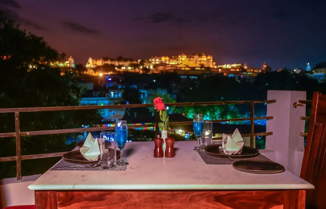 Table set on the Jaajam rooftop with the lit City Palace behind