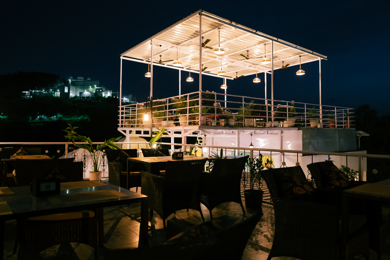 Table set on the Jaajam rooftop with the lit City Palace behind