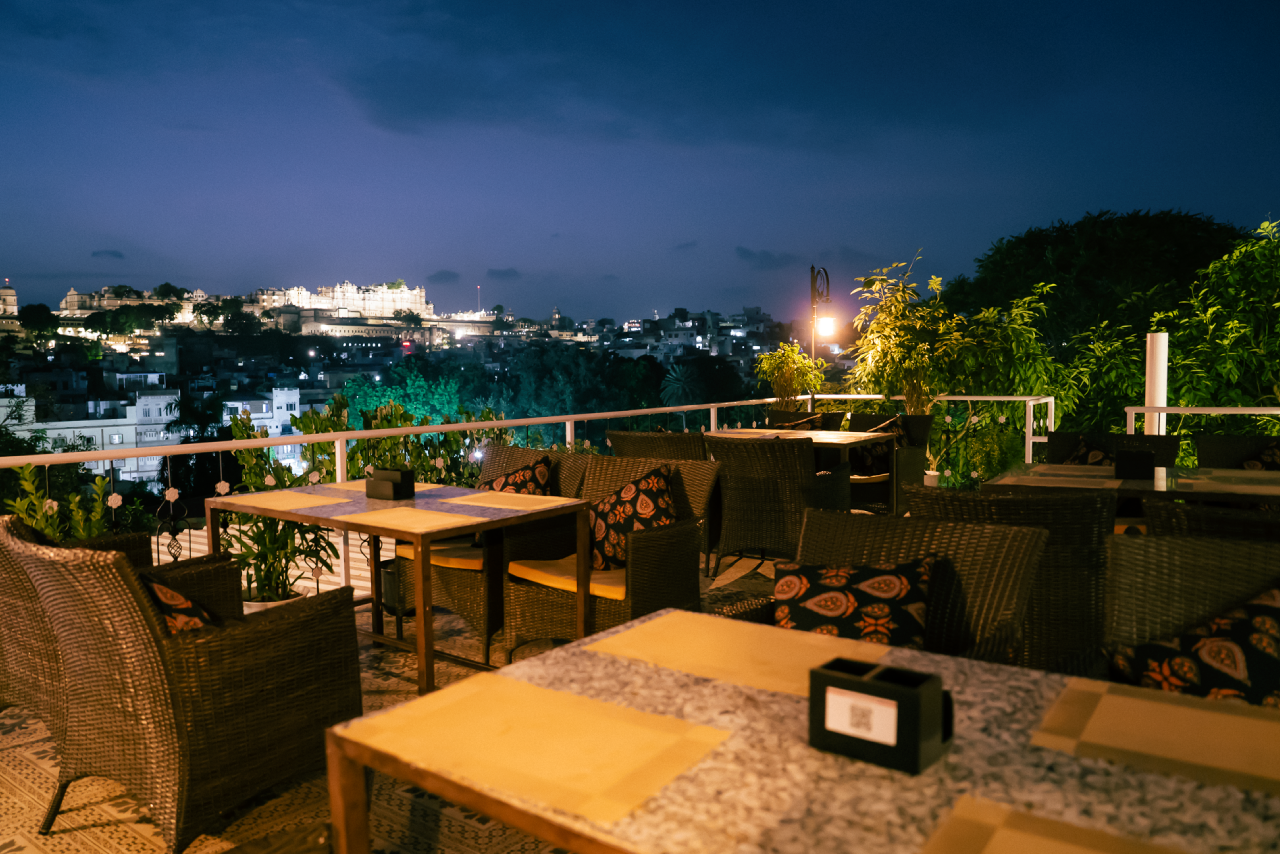 Table set on the Jaajam rooftop with the lit City Palace behind